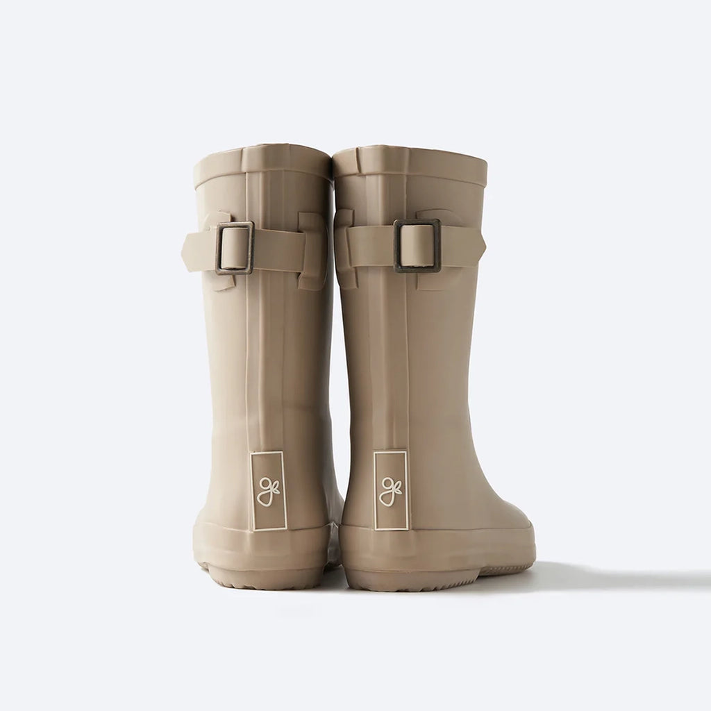 goumikids Dune Muddies Rain Boots Children's Rubber Boots. Beige rubber rain boots for children. Goumi label debossed in white rectangle. Adjustable buckle on back of boot. Back view.