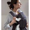 mom smiling with baby in mini baby carrier by babyBjorn in anthracite