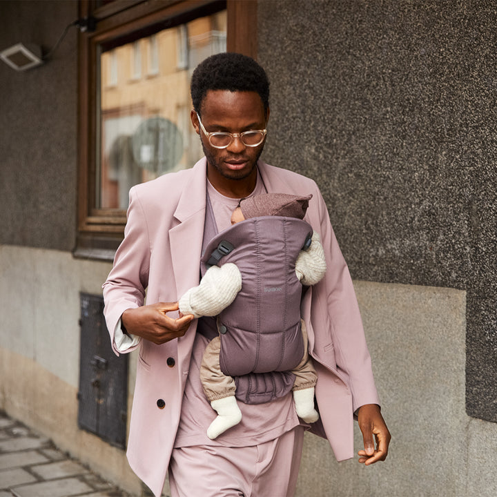 parent walking outdoors with infant in Baby Bjorn dark purple baby carriers