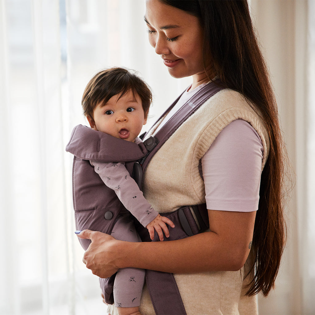 mom and playful infant in babybjorn purple mini baby carrier