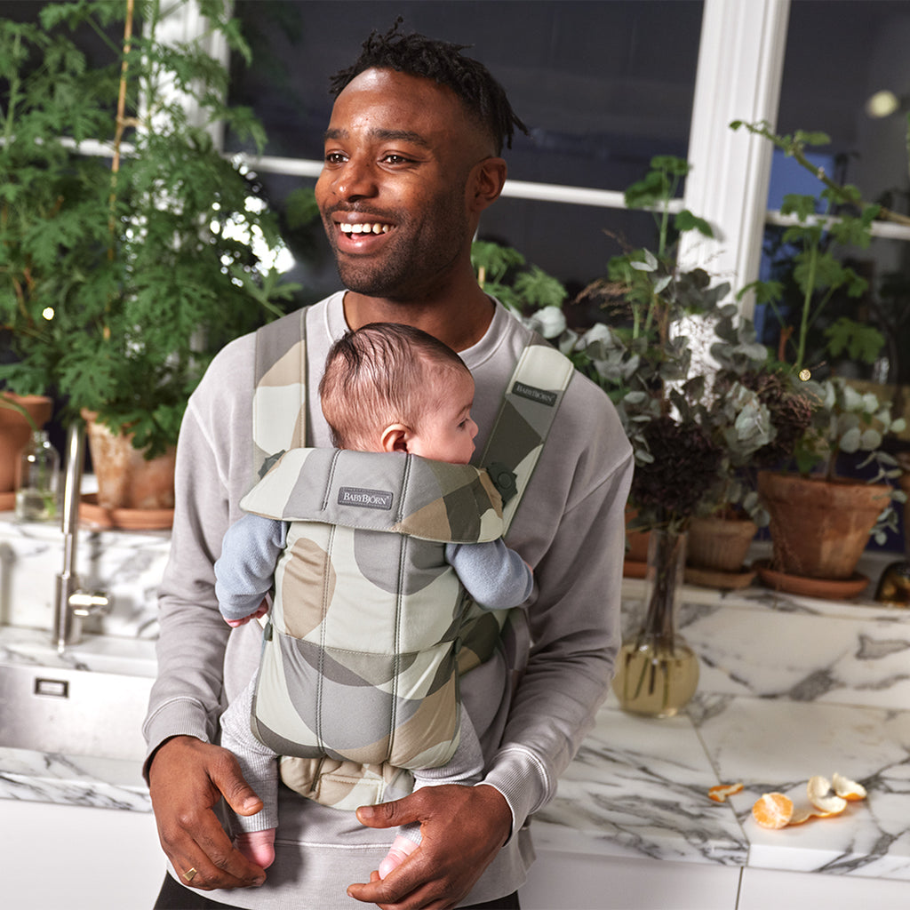 dad smiling with infant in babybjorn khaki green baby carrier mini