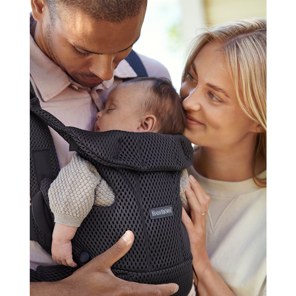 parents watching baby sleep in baby bjorn free baby carriers