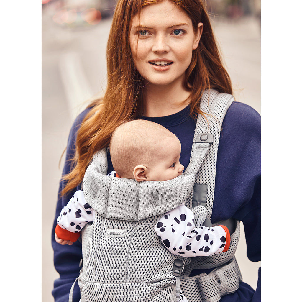 mom holding infant in baby bjorn carrier free grey