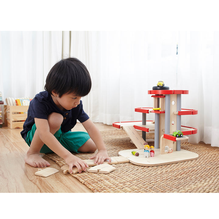 A kid-friendly wooden parking garage with multiple levels and vehicles for pretend play.