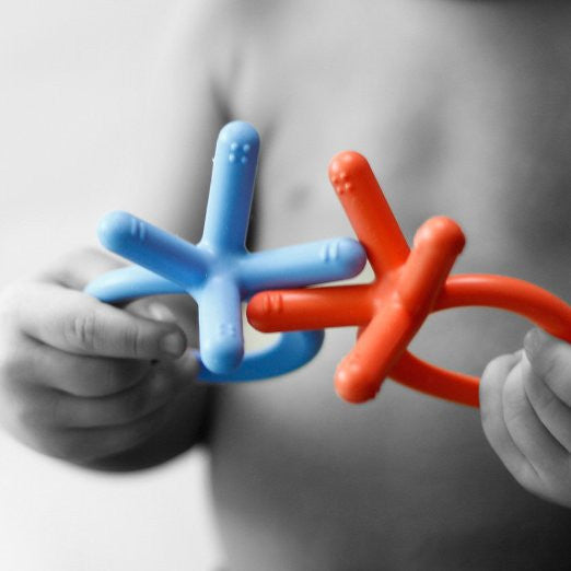 Toddler holding Comotomo baby teethers for gum comfort