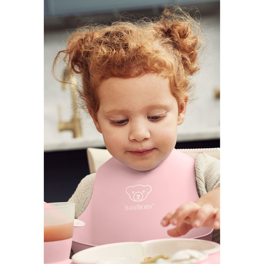 Baby Using Babybjorn Soft Feeding Bib Set in Pink, ensuring comfort and minimal mess