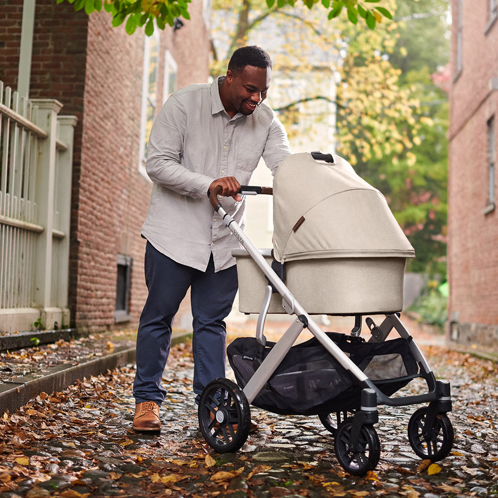 Man walking with Uppababy vista stroller in Declan with Bassinet accessory