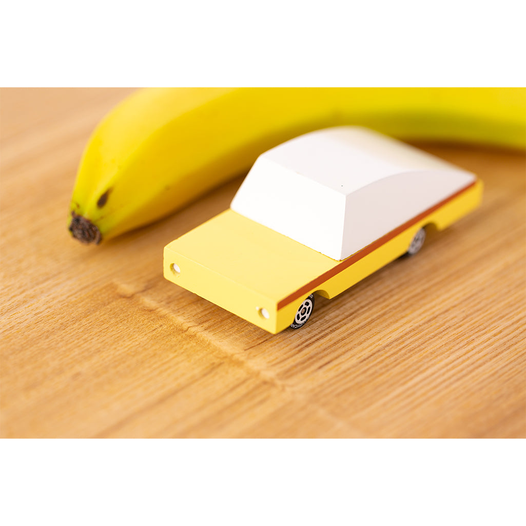 Wooden banana car by Candylab, displayed with a banana on a natural wooden surface.