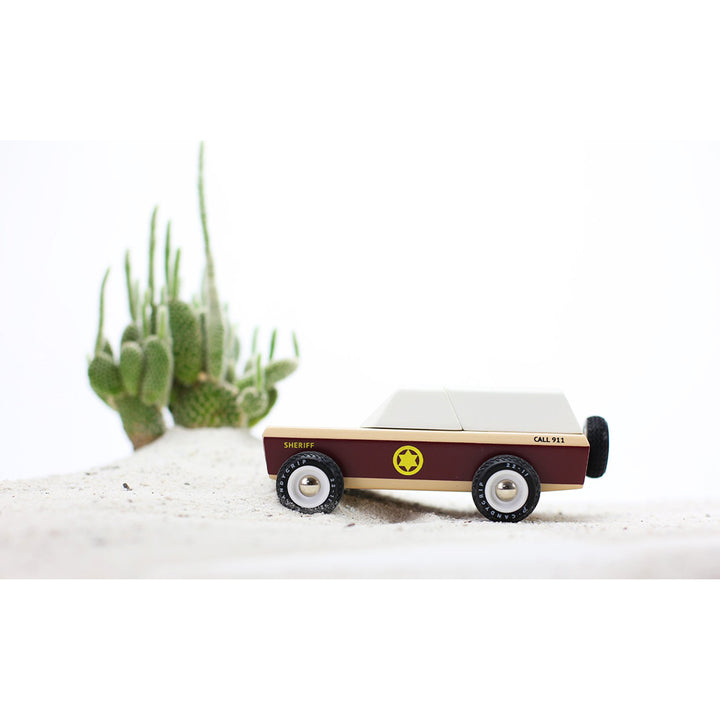 Wooden Lone Sheriff car by Candylab, displayed on a sand play surface.