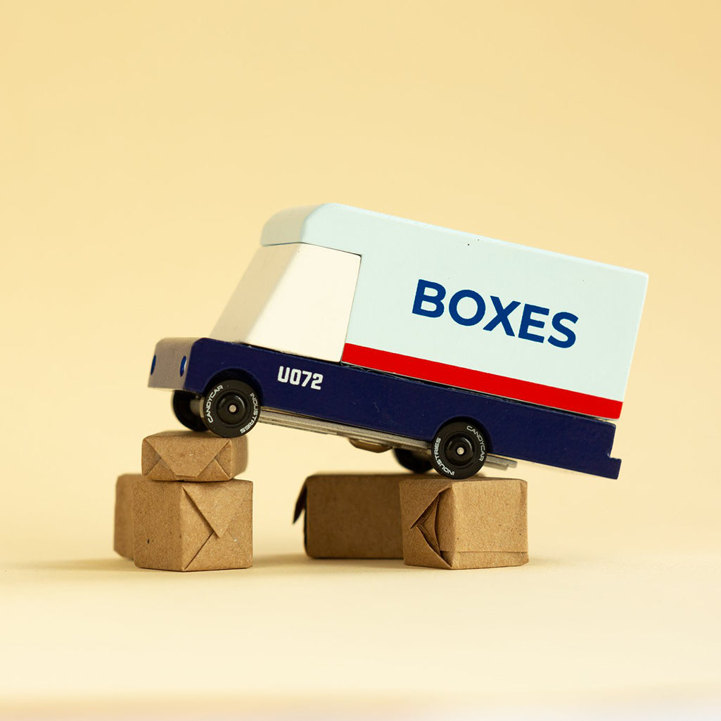 Mail van toy by Candylab, displayed on top of miniature toy boxes.