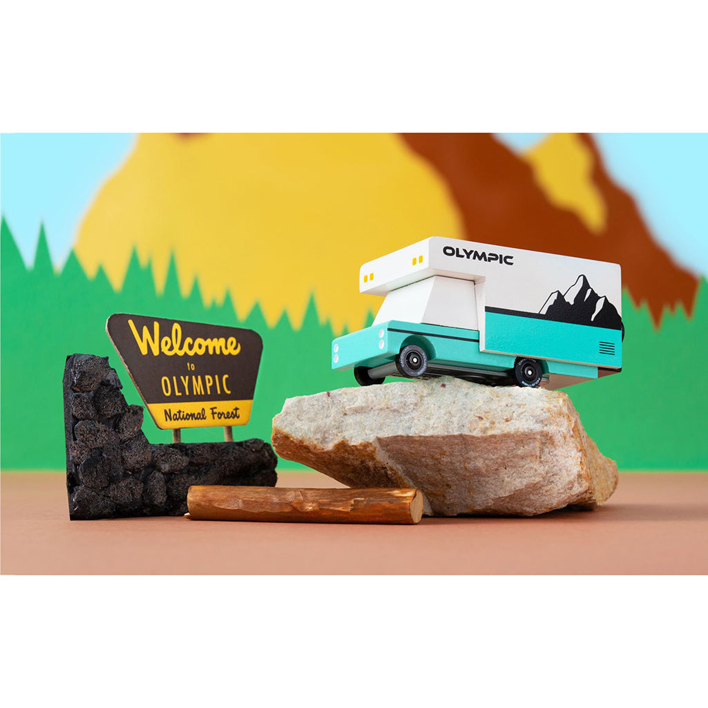 Candylab Toys Olympic RV wooden car toy placed on a rock, emphasizing its outdoor adventure theme