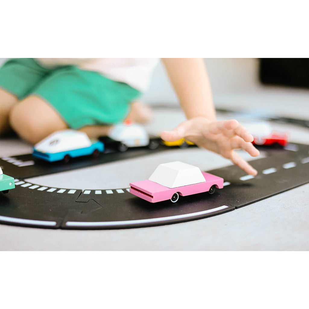 A Candylab Toys pink sedan wooden car speeding along a toy track, providing fun for young children.