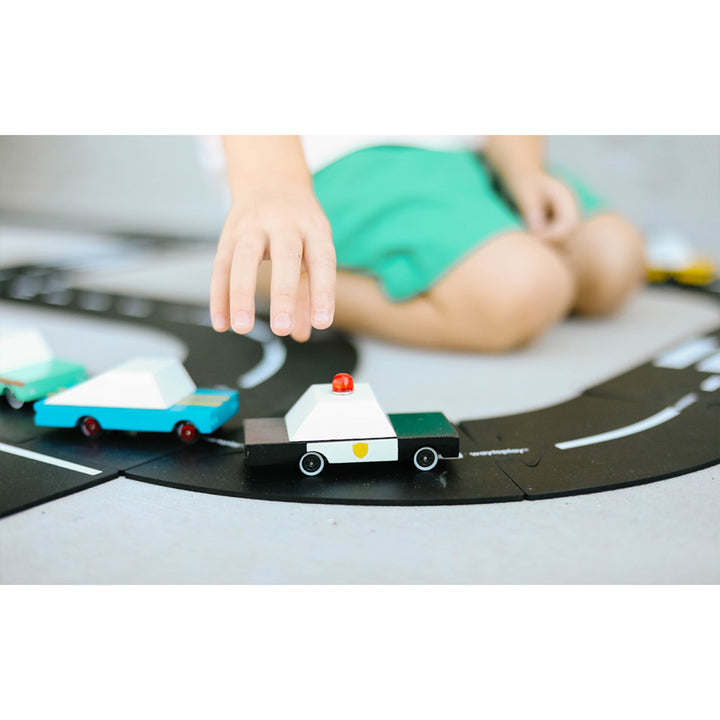 A child playing with a wooden Candylab police car, engaged in imaginative law enforcement adventures.