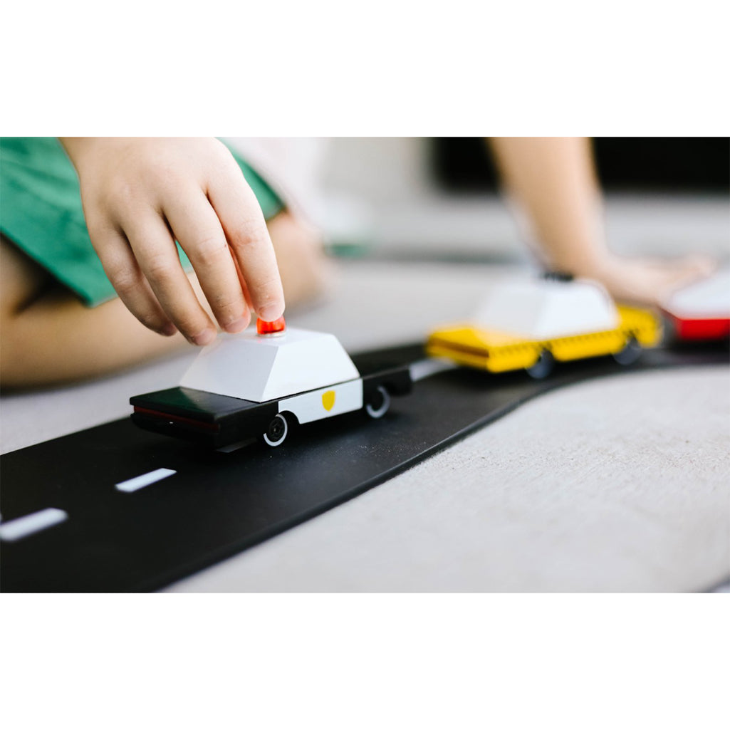 A Candylab Toys police car moving along a toy track, perfect for kids to interact with during playtime.