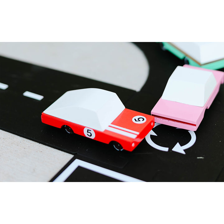 A Candylab Toys Red Racer #5 wooden car speeding along a toy track, perfect for kids playtime racing.