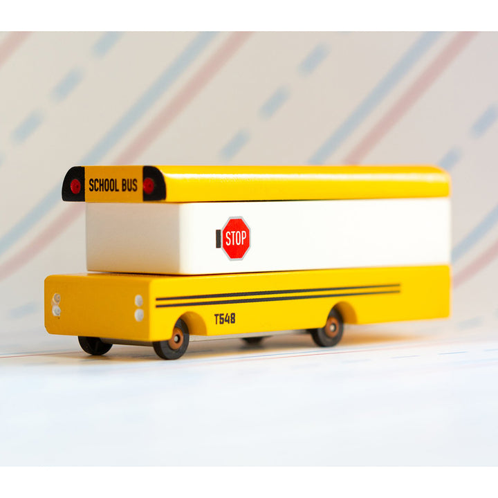 A wooden yellow school bus toy by Candylab Toys, perfect for children's pretend play adventures.