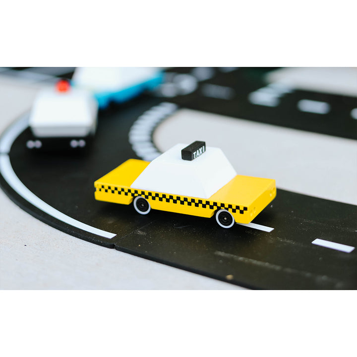 Candylab Toys Wooden Yellow Taxi Car on a track, enhancing pretend play with a cityscape setting