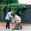 Man Walking with Uppababy Cruz Stroller with Bassinet Accessory in Anthony