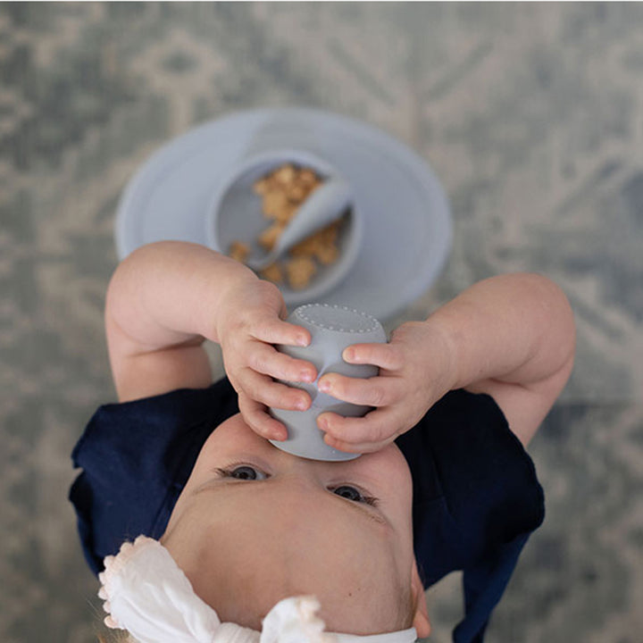 Baby using the EZPZ Silicone Tiny Cup for Infants & Toddlers, among the best practical sippy cups for babies at mealtime