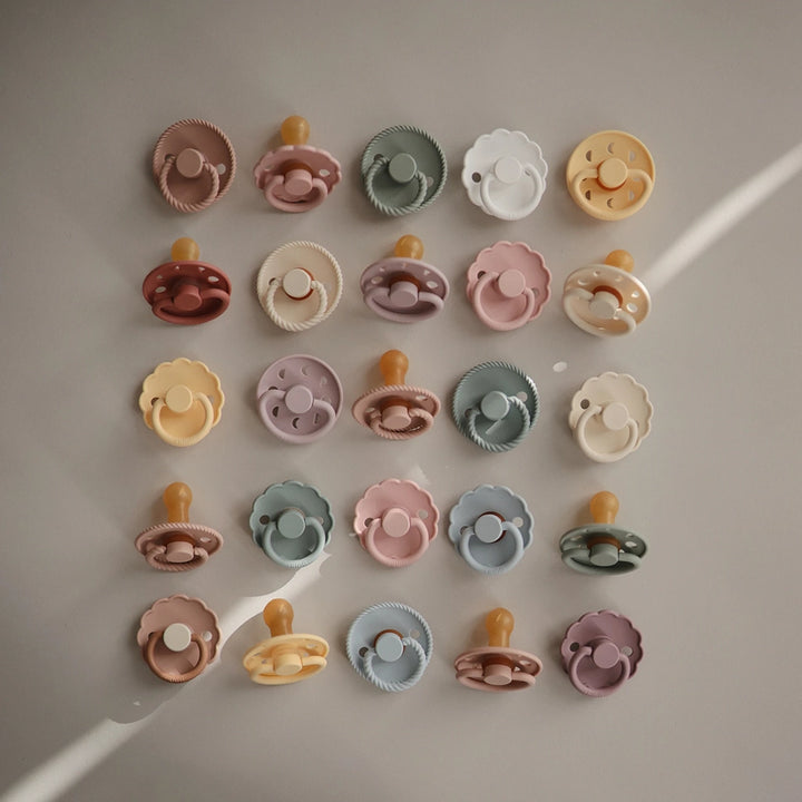 FRIGG Baby Pacifier pictured with various colored pacifiers.