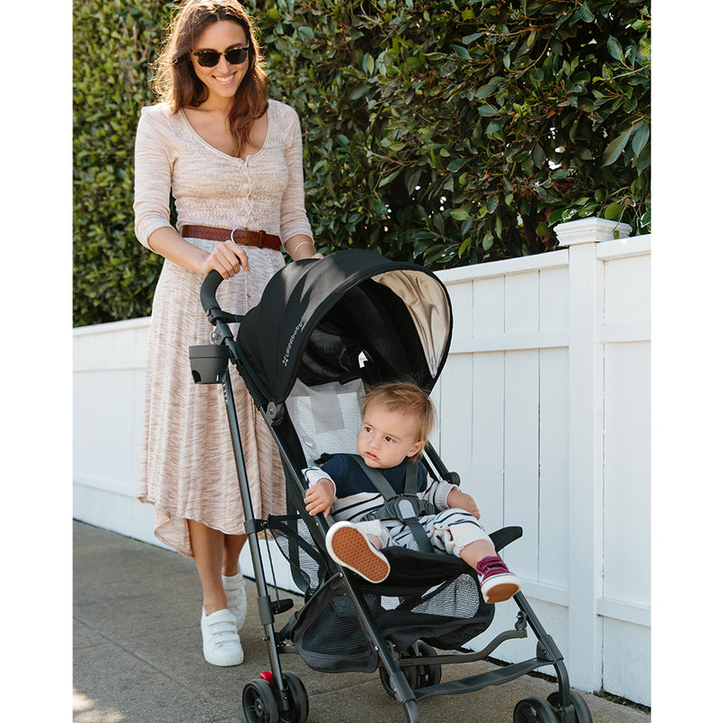 Mom pushing baby in UPPAbaby G-Lite Lightweight Stroller in black