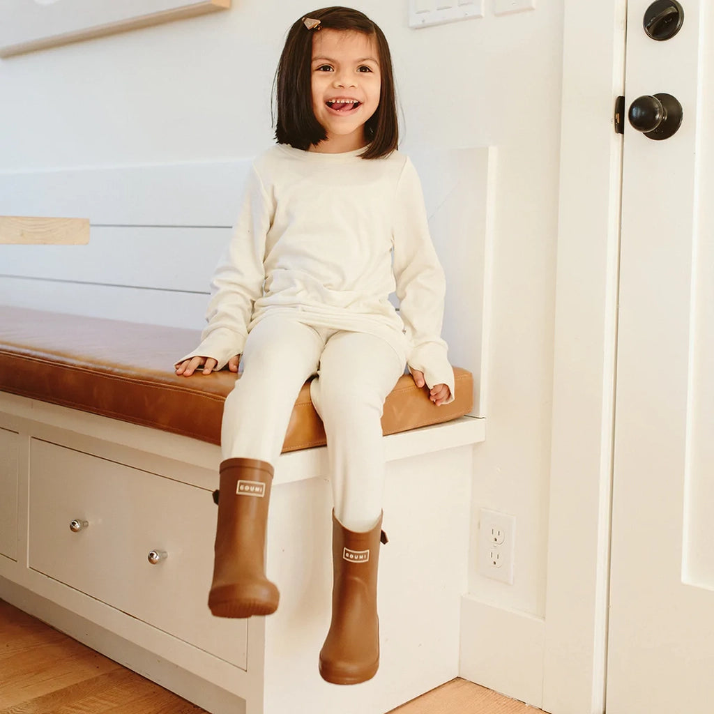 Lifestyle image of child wearing Sienna Muddies inside, sitting on kitchen counter.