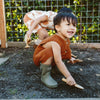 Lifestyle image of toddler wearing goumikids Muddies Artichoke boots in the mud outside.