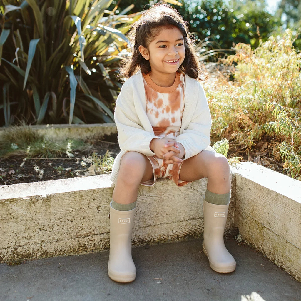 Lifestyle photo of child wearing Dune Muddies while sitting outside.