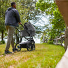 Man Pushing Uppababy Cruz Stroller with Bassinet Accessory in Greyson