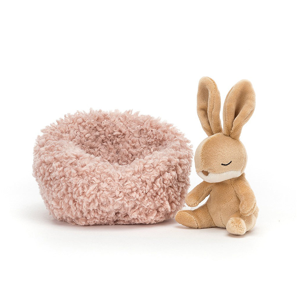 Jellycat Hibernating Bunny Stuffed Animal Children's Toy. Removable caramel colored rabbit plushie with a soft pink sherpa nest. 