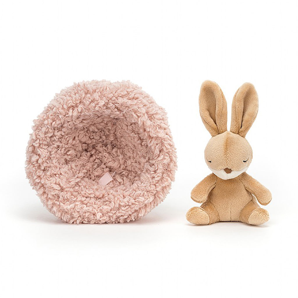 Jellycat Hibernating Bunny Stuffed Animal Children's Toy. Removable caramel colored rabbit plushie with a soft pink sherpa nest.