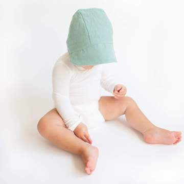 child looking down while wearing KyteBaby Linen Baby Bonnet Hat 