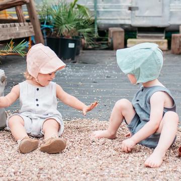 two children playing while wearing KyteBaby Bonnet Hat