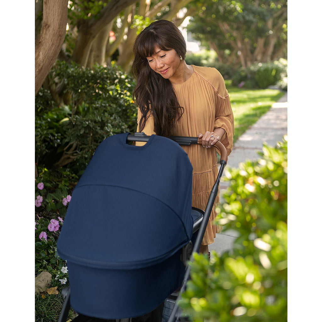 Woman Pushing Uppababy Cruz Stroller with Bassinet Accessory in Noa Blue