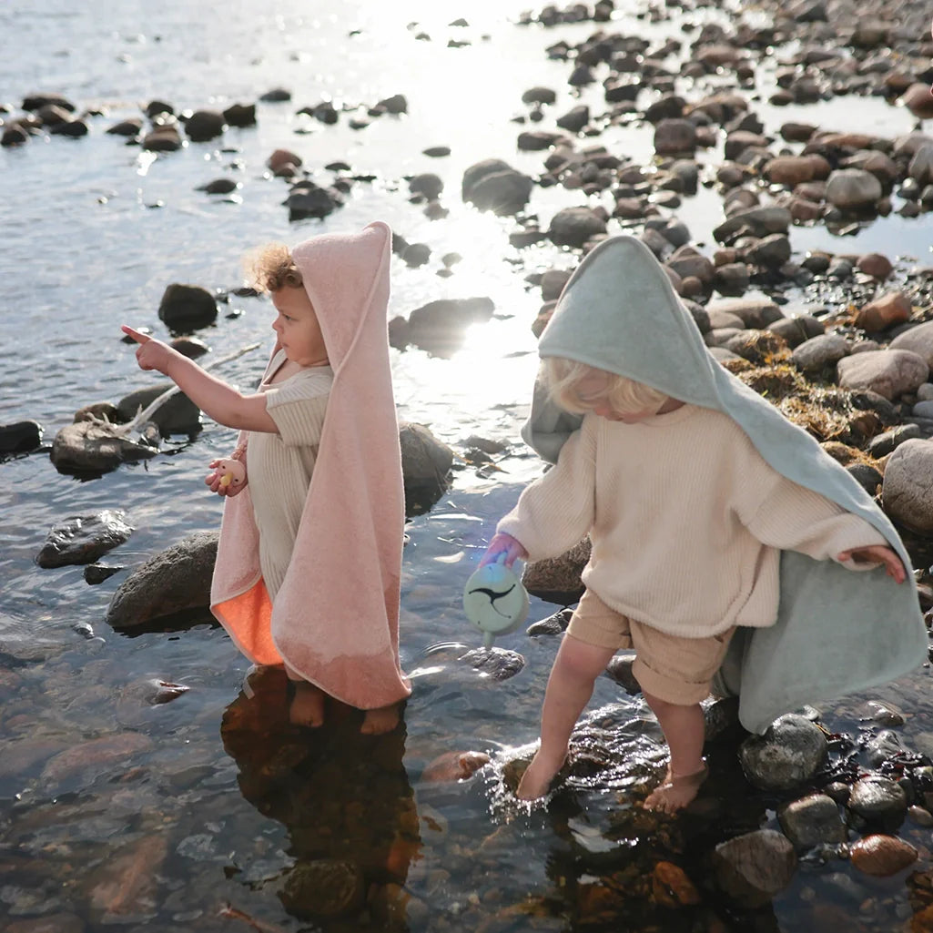 Baby wrapped in a soft gray Mushie towel for a perfect bath time experience