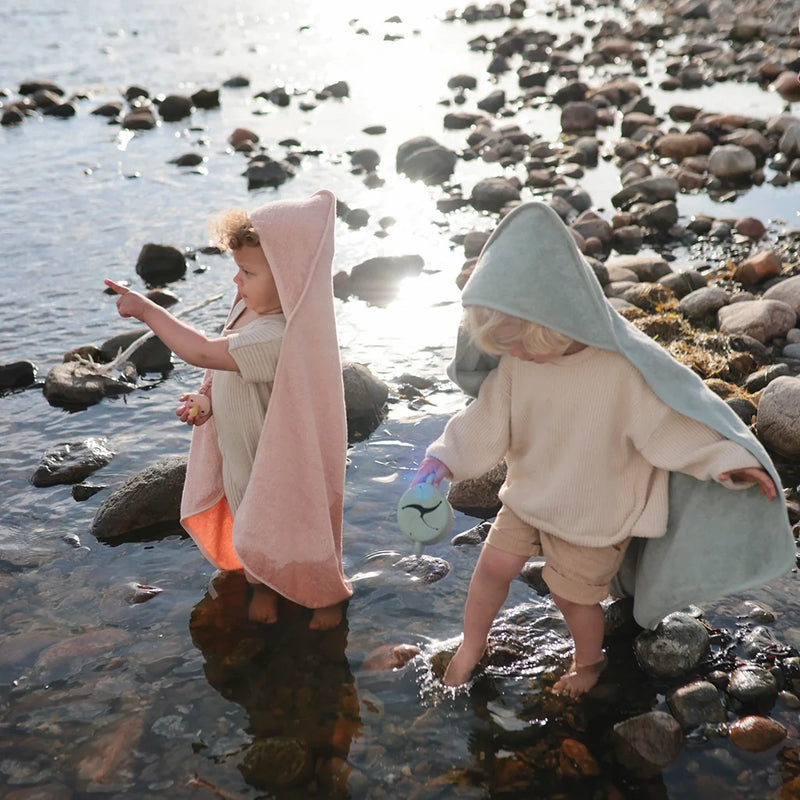 Baby wrapped in a soft gray Mushie towel for a perfect bath time experience