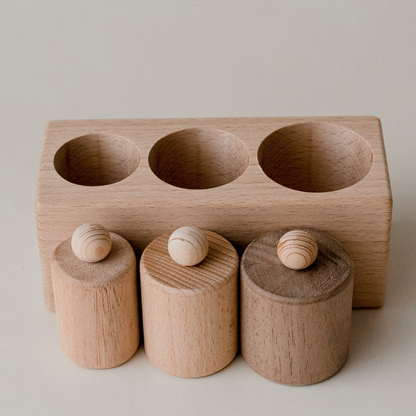 3 cylinder blocks made of wood with wood balls on top and a base with three craters for cylinders. childrens wooden toy set