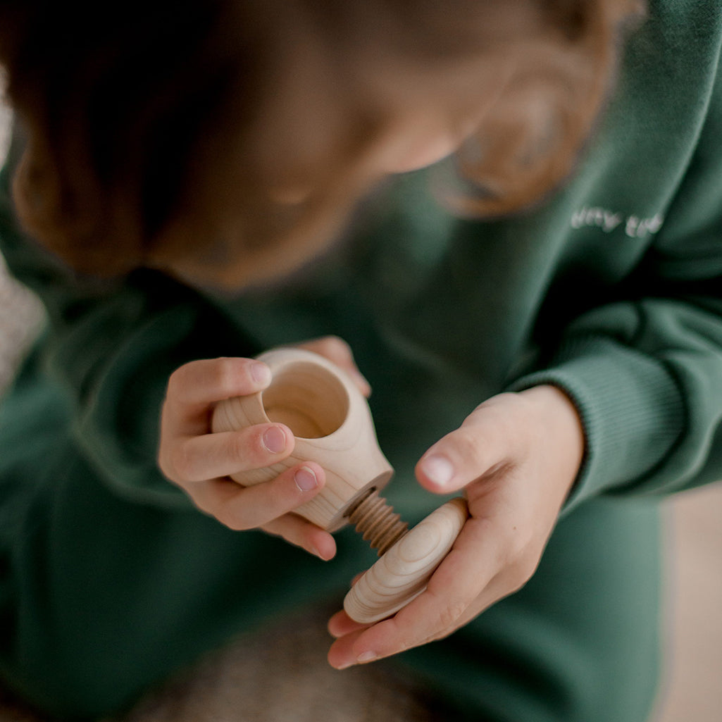 QToy Wooden Screw Mushroom Toy 2 Piece Set. Infant Babt Toy for Fine Motor Skills and development. Birds Eye View of child in green sweats playing with toy
