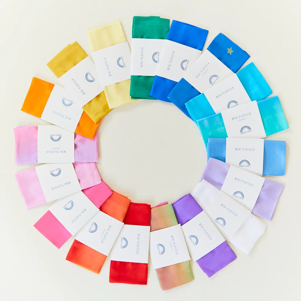Image of all color variations currently available for Sarah's Silks Mini Playsilks laid out in a circular fan; in their packaging.