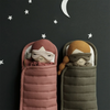 Clay sleeping bag shown with doll inside, next to Olive colored sleeping bag with doll.