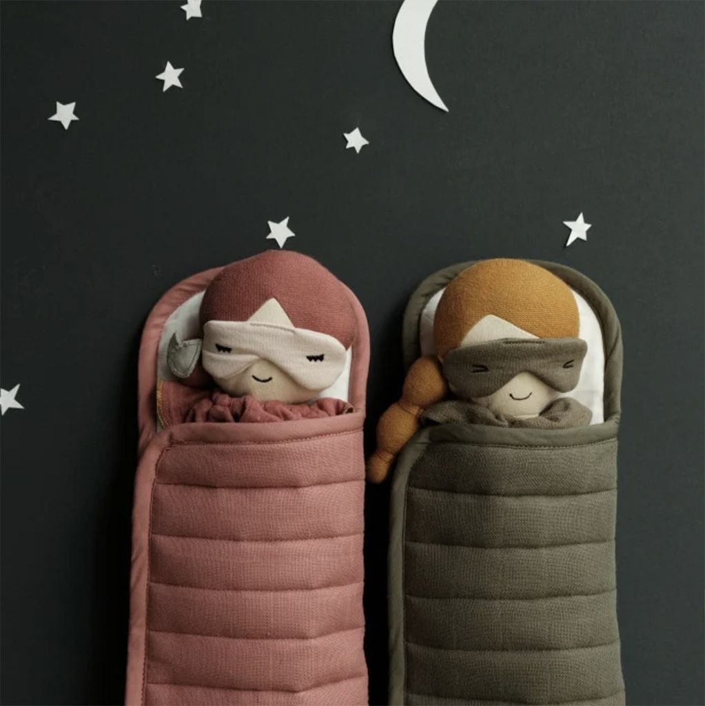 Clay sleeping bag shown with doll inside, next to Olive colored sleeping bag with doll.