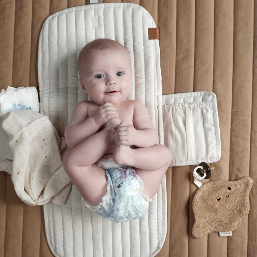 Fabelab Chambray Blue Spruce Infant Changing Mat. Lifestyle image of infant laying on open changing mat.