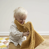 Fabelab Ochre Grid Fold-over Infant & Toddler Feeding Bib. Modeled on child playing.