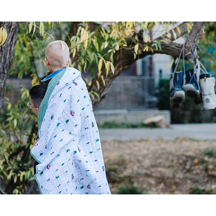 Little Unicorn Muslin Quilt in Powder Party brings winter fun to this premium organic cotton baby blanket.