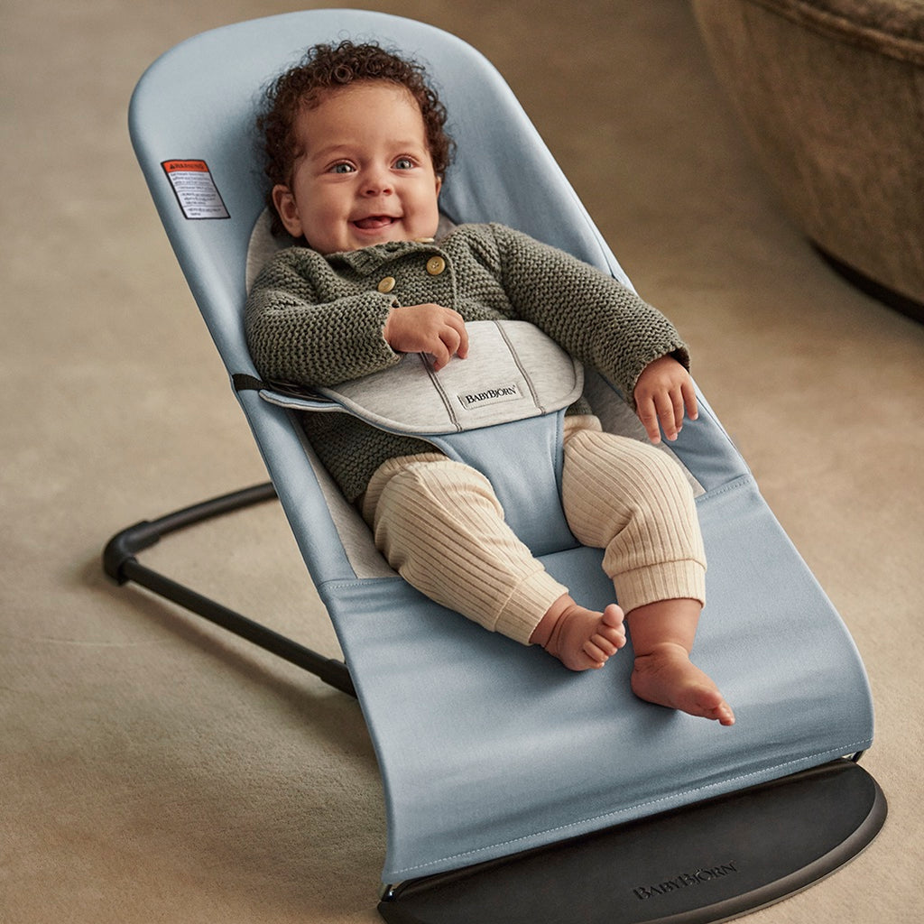 smiling infant in baby bouncers seat by BabyBjorn blue grey