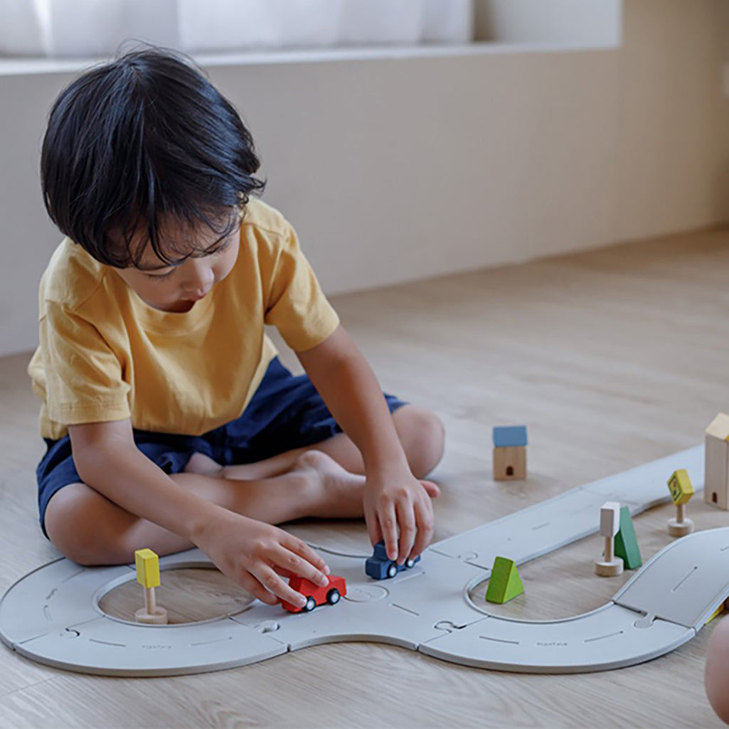 A child interacting with the Plan Toys railroad expansion set for toy trains, building a fun track layout.