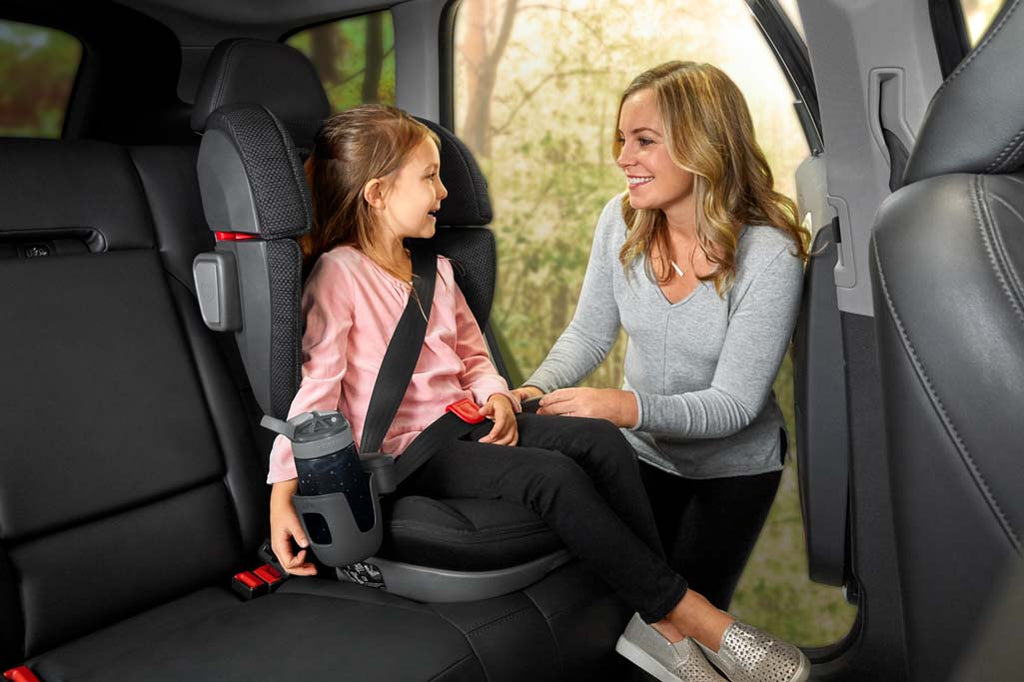 Mom buckling child into Uppababy Alta Booster Seat with Cupholder