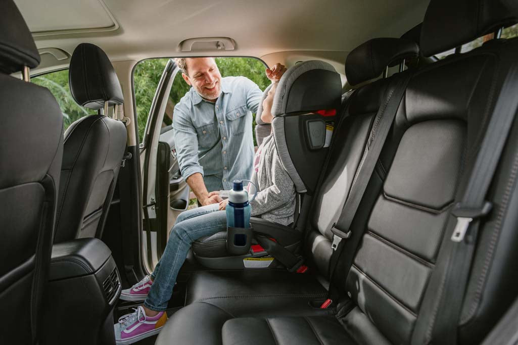 Parent smiling at child in Uppababy Alta booster seat in car