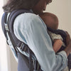 side view of mom snuggling newborn in baby bjorn carrier