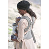 mom carrying infant with view of back straps of babybjorn carrier